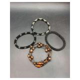 Grouping of (3) beaded mesh bangles and (1) multi-strand wrap bracelet featuring copper, amber-toned glass, and black beads