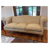 Chippendale-Style Camelback Sofa with a curved back, rolled arms, patterned yellow/gold upholstery, and carved wooden legs