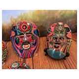 Vintage set of four hand-painted Mexican red clay mask. The smallest in front has been repaired.