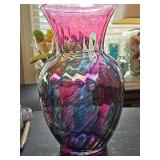 Translucent art glass vase featuring a flared pink or cranberry rim and a vibrant multi-color watercolor or drip-style swirl pattern. 11 in tall.
