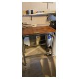 Metal table with rolls of plastic and sewing