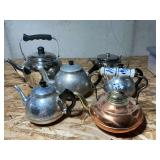 Copper, aluminum and stainless teapots with tea cozies