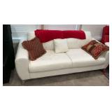 White 100% leather sofa with red throw and throw pillows