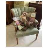 Green upholstered chair with throw pillows and teddy bear