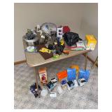 Card table and contents includes solar emergency radio, Zebco collapsible fishing rod, tennis racket, Banjo Bros bike bag, portable LP burner and more