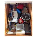 Contents of kitchen drawer includes mini baking pans, apple corer, Pampered Chef crinkle cutter, oven liners, tools, etc