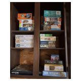 Cupboard full of puzzles including Gone with the Wind on the floor
