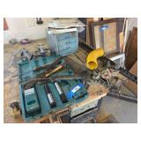 Corner of tool bench includes Makita battery operated drill, some hand tools, corner squares, saws, and more