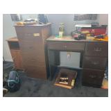 Small kneehole desk with a few desk supplies, four drawer particleboard dresser, and particleboard side table