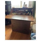 Light duty particle board drop front desk with three drawers and some basic desk supplies