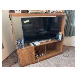 TCL 42 inch flatscreen Roku TV, a few DVDs and particleboard entertainment center