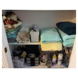 Hall closet treasures, including lightbulbs, home hardware type items, bath towels, and rugs