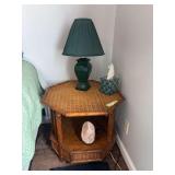 Wicker style vintage side table with pair of green ceramic table lamps, a salt lamp, and all miscellaneous artwork