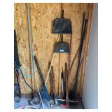 Tools in garage corner includes ax, splitting mall, Matic, broom, dust pans, heavy spud bars