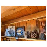 Shelf full of cabin decor includes some wall art, petrified wood, cast-iron snake, antler handle firestarter
