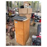 Custom-made four drawer file cabinet plus box full of desk items, including computer monitor, keyboard, some handheld telephones, and a briefcase