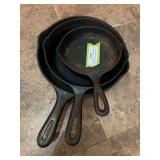 Three small cast-iron skillets, # five and six and the smallest is marked Lodge