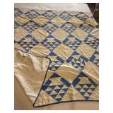 Vintage hand-stitched 73x82 blue and cream pinwheel quilt shows wear, including holes in both the blue and cream sections.