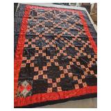 Handmade quilt features a striking black and red checkerboard pattern with contrasting floral backing. 87x68