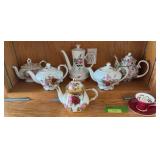 Teapot collection and lone cup w/ saucer