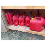 Six gas cans mostly full in shed by camper