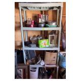 Plastic shelving unit with various kitchen wares on shelves includes bread maker, waffle maker, food sealer, barbecue thermometer, cookie jar, serving items, pots and pans