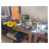 Table top full of hardware, screws, shrink wrap, ladder workstations, stapler, hinges, sandpaper, cabinet hardware
