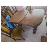 Antique Wooden dining table featuring a double-pedestal or trestle-style base with scrollwork and claw or scrolled feet 44x66 without the leaves inserted. With six chairs and two leaves and padded top