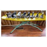 (8) CLOTHES IRONS AND AN IRONING BOARD