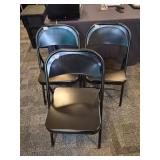 Three black metal folding chairs, in near perfect
