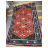 Handwoven wool Turkish rug has fringe.   Rug