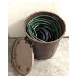 Garbage can with lid full of garden hoses