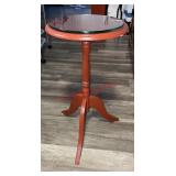 red pedestal side table with a glass top.
