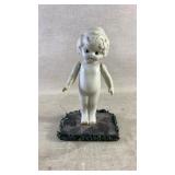 A vintage bisque doll on display stand