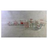 Seven measuring cups including Pyrex and anchor