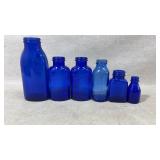 Six Blue Glass Bottles of Varying Sizes