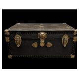 Vintage black steamer trunk featuring brass