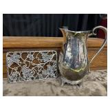 A silver-plated pitcher and trivet.
