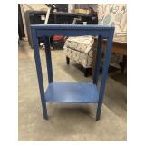 Blue accent table features a lower storage shelf