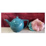 Teal ceramic teapot and pink hibiscus planter.