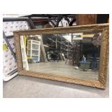 Ornate gold-gilded wood and gesso wall mirror.