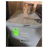 Two door file cabinet, folding chair, pair of scissors and a planter