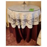 Decorative accent table with white lace overlay covering a dark red tablecloth