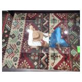 vintage cowboy-themed coffee table featuring a sculpted, hand-painted cowboy figure as the base supporting a glass top