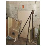 vintage or antique metal frame assembly, such as a tripod stand, tool arm, or support structure alongside a weathered basin and panel