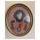 This image shows a vintage round wall hanging with a pink velvet background, ornate gold-tone frame, and inset romantic art prints.Appears to be a vintage Victorian-style wall decor piece featuring tr