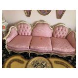 The image appears to show an ornate vintage French Provincial or Rococo-style tufted pink sofa with a carved off-white or cream wooden frame.