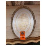 The image shows a vintage oval vanity or dresser tray featuring an ornate gold-tone metal filigree rim and a decorative floral motif on the base.Style: Mid-Century Hollywood Regency or Rococo Revival 