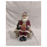 Santa Claus Figurine Seated on Bench Holding Wrapped Gift